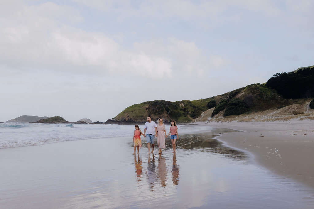 Family walking along Ocean Beach Whangarei during a portrait session.