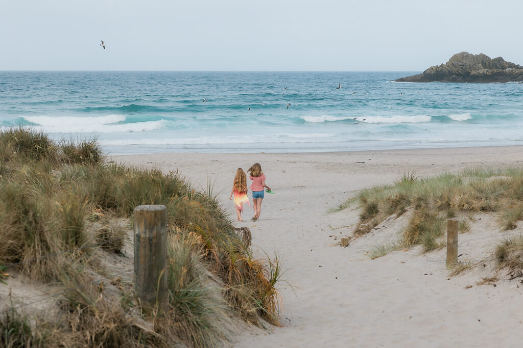 Two tween girls at Ocean Beach Whangarei at the start of their family photo session.