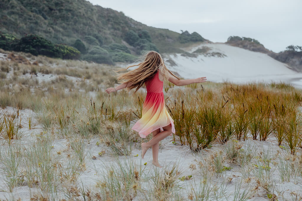 Young girl twirling at Ocean Beach Whangarei