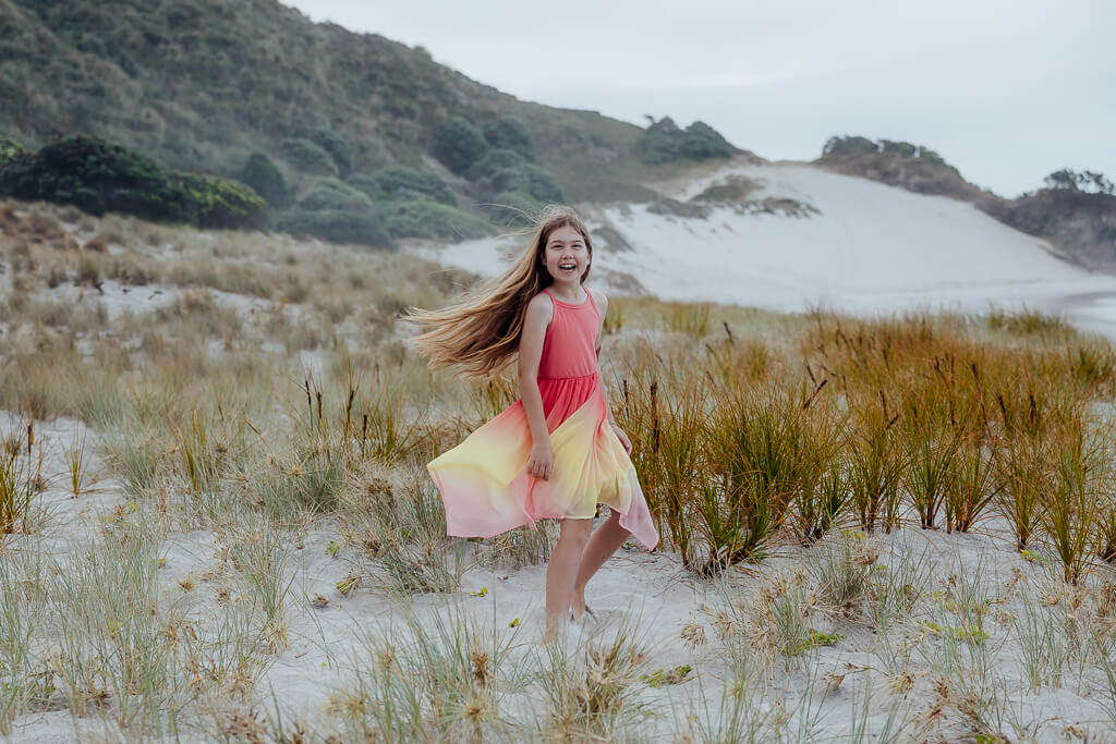 Young girl twirling at Ocean Beach Whangarei